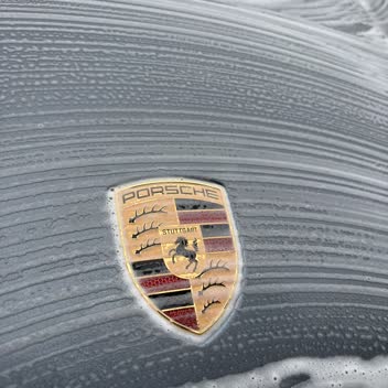 Snow foam sheeting off a Porsche crest during a hand wash.
