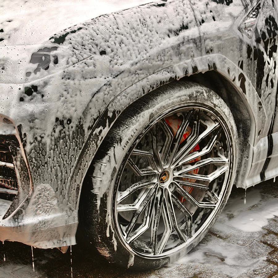A foam-covered wheel and arch during a hand wash.